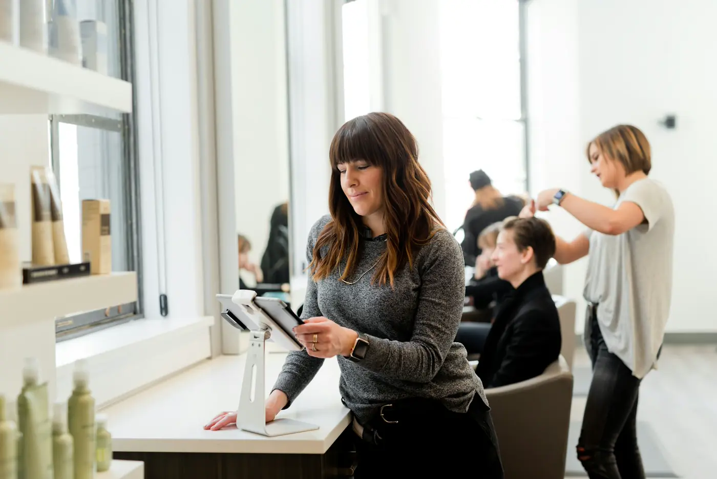 Salon owner checking appointments on a tablet beside her chair
